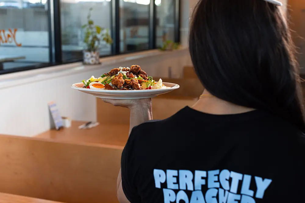 Waitress working at Yolks Breakfast bringing a delicious breakfast plate to a table
