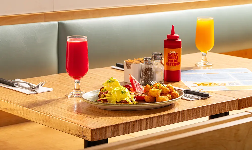Brunch table with eggs benedict and drinks in a modern restaurant setting showcasing breakfast franchise opportunities