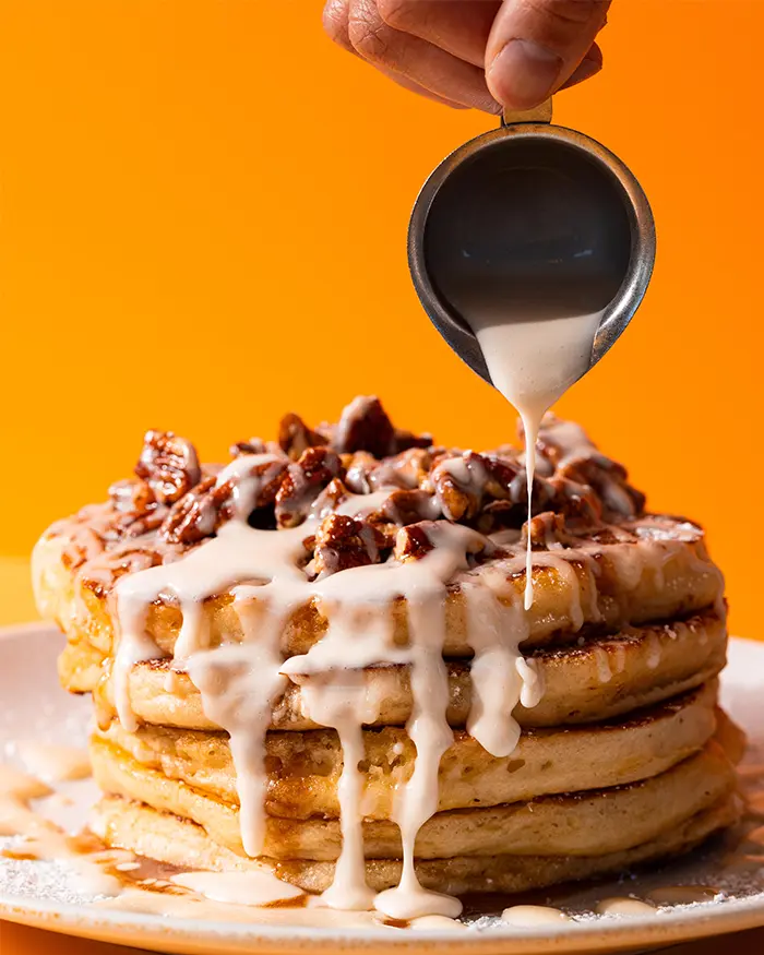 Cinnamon roll pancakes with icing being poured on top at Yolks Breakfast Canada