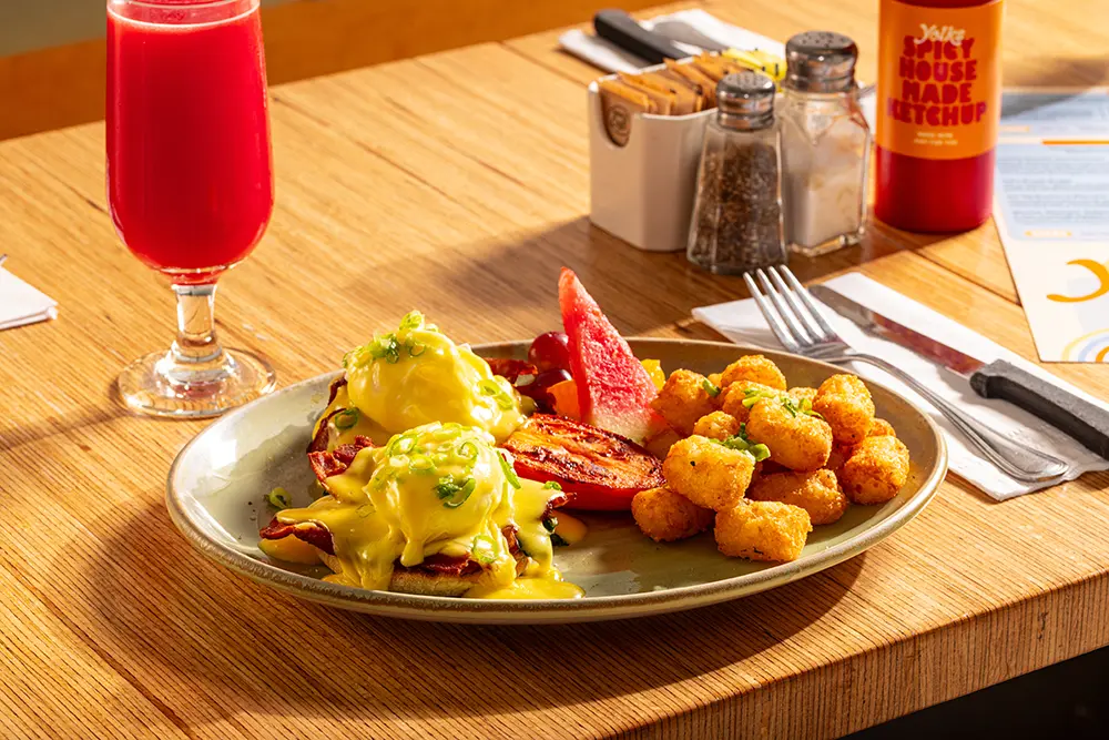 Fresh Eggs Benedict with perfectly poached eggs, hollandaise sauce, and crispy breakfast potatoes served at Yolks.